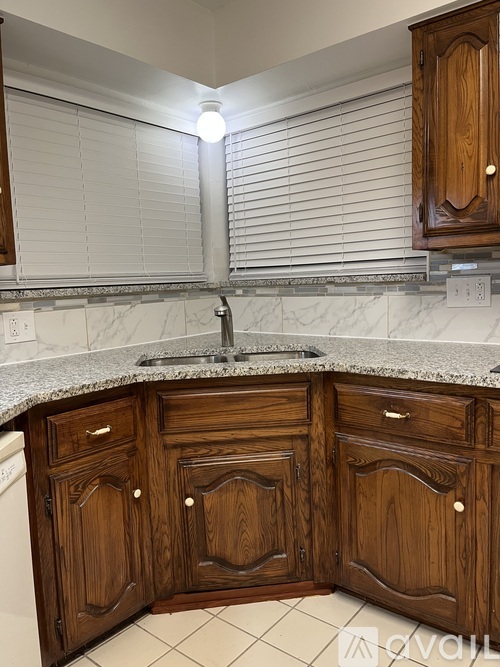 A kitchen with wooden cabinets and a marble countertop.