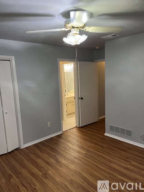 A room with wooden floors and a ceiling fan with lights.
