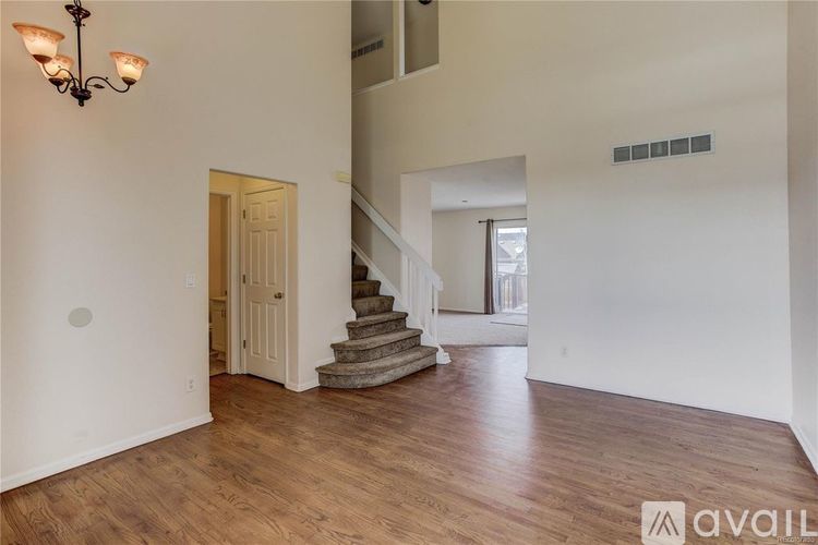 A spacious room with wooden floors and a staircase leading to another room.