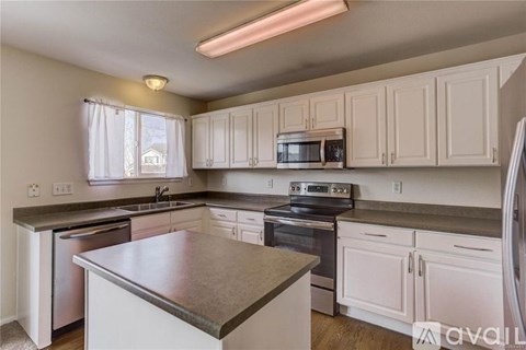 A kitchen with white cabinets and a stainless steel island.