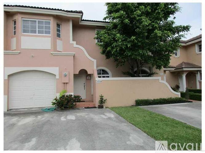 A house with a white garage door and a tree in front.