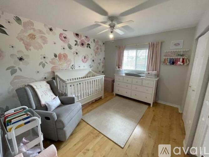 A baby nursery with a floral wallpaper and a white crib.