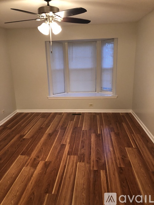 A room with wooden flooring and a ceiling fan.