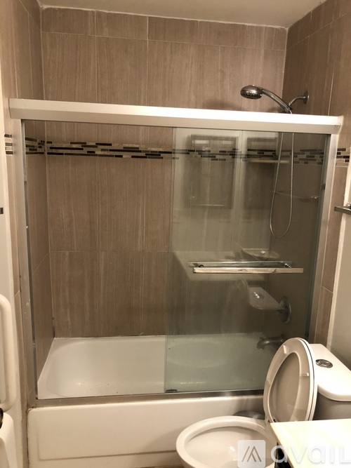 A white toilet is in a small bathroom with a walk-in shower.