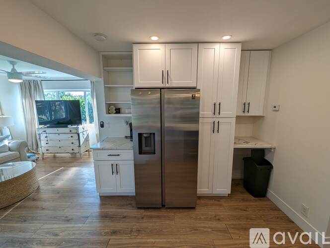 A kitchen with white cabinets and a stainless steel refrigerator.