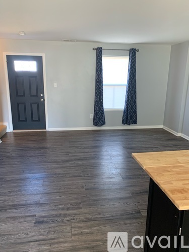 A room with a black door and wooden flooring.