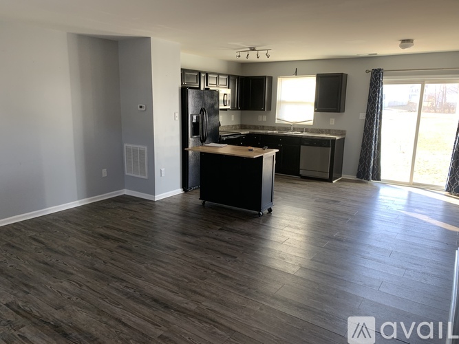 A kitchen with dark wood floors and a black refrigerator.