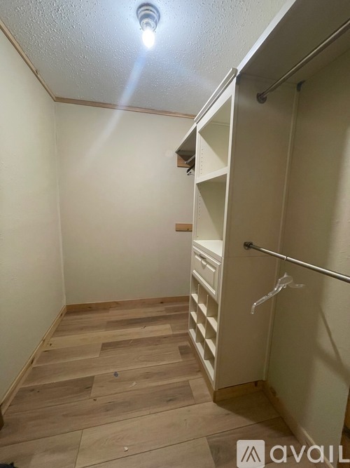 A hallway with a wooden floor and a white wall.