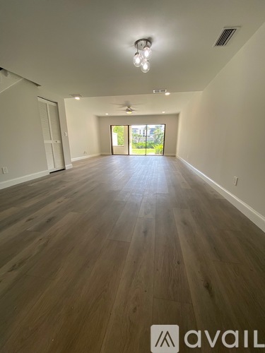 A spacious room with wooden flooring and a ceiling fan.