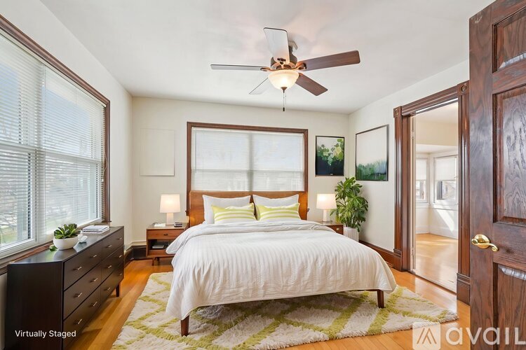 A bedroom with a large bed, a ceiling fan, and a dresser.