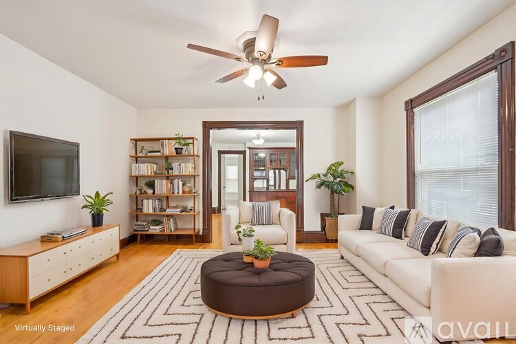 A living room with a white couch, a round coffee table, and a ceiling fan.