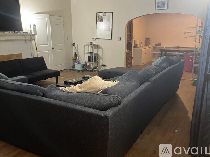 A living room with a grey couch and a television on the wall.