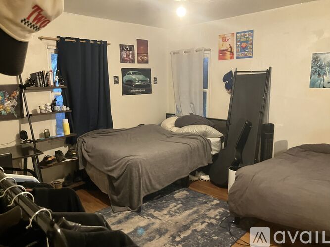 A bedroom with a bed, a dresser, and a wall with pictures and posters.