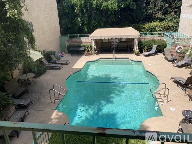 A pool with a canopy and lounge chairs.