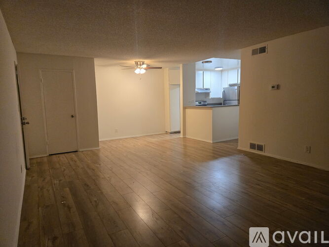 A spacious room with wooden flooring and white walls.