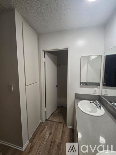 A bathroom with a sink, mirror, and wooden floors.
