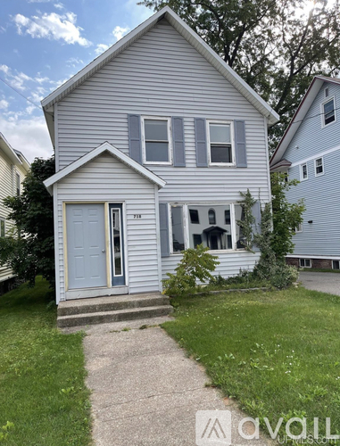 A house with a grey siding and a white door is shown.