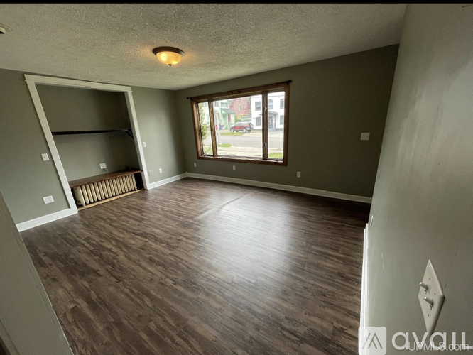 A room with wooden flooring and a window overlooking a street.
