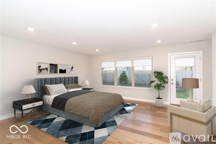 A bedroom with a large bed and a window overlooking a green area.