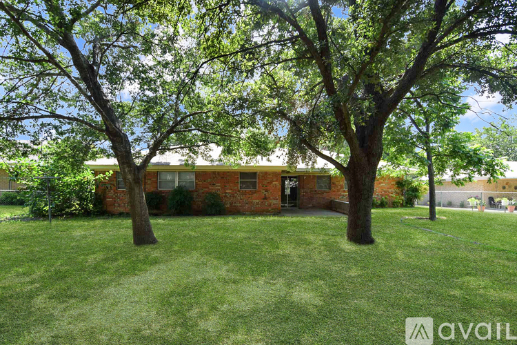 A house with a green lawn and trees in front.