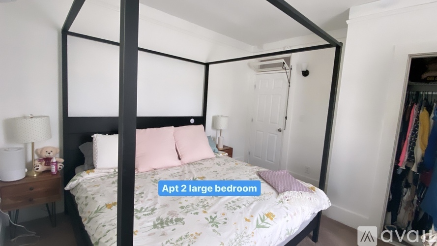A bedroom with a four poster bed and a teddy bear on the nightstand.