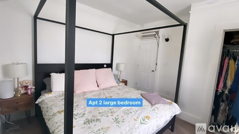 A bedroom with a four poster bed and a teddy bear on the nightstand.