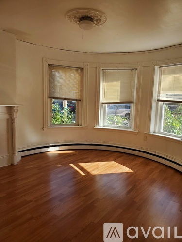 A room with wooden floors and three windows.
