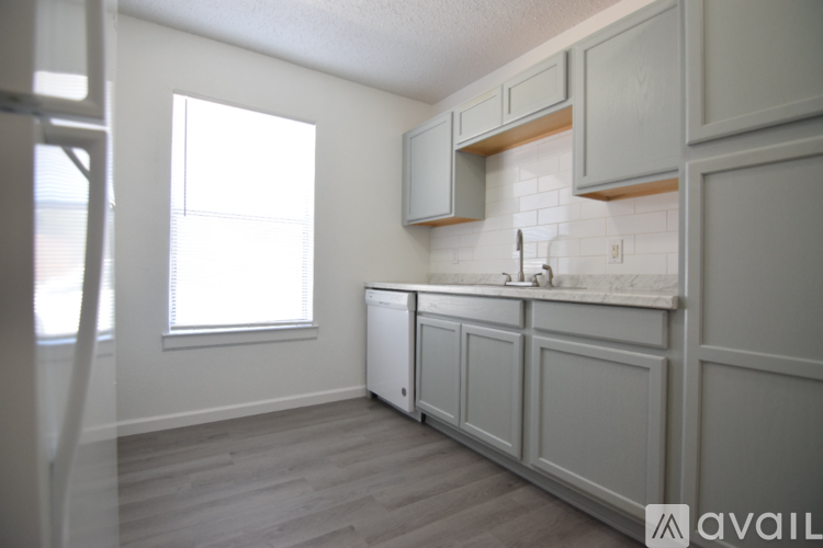 A kitchen with white cabinets and a window.