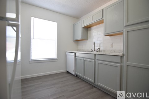 A kitchen with white cabinets and a window.