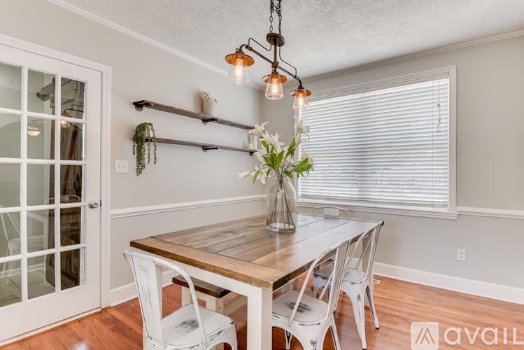 A dining room with a wooden table and white chairs.