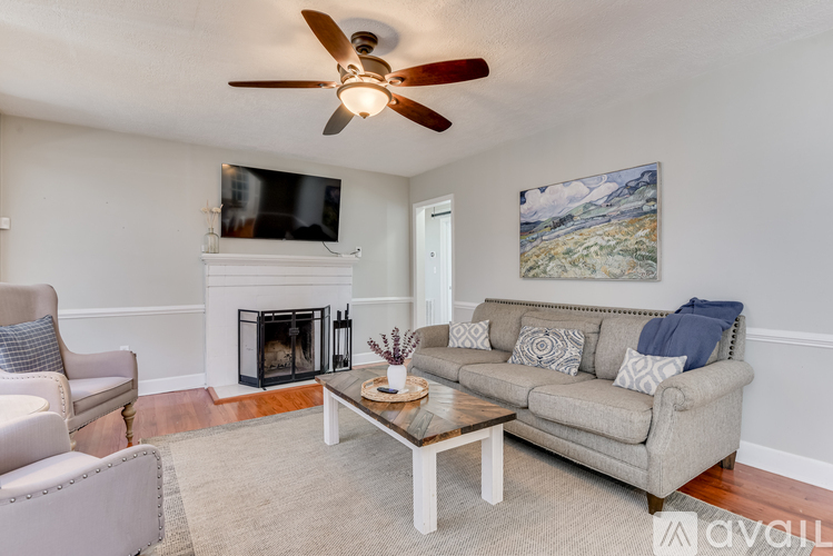 A living room with a grey couch, a coffee table, a fireplace, and a painting on the wall.
