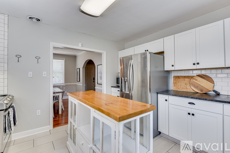 A kitchen with white cabinets and a wooden island.