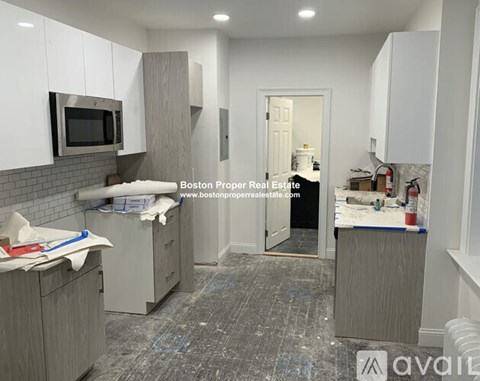 A kitchen under renovation with a website address for Boston Proper Real Estate.