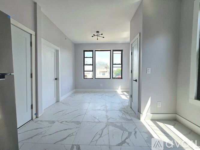 A spacious room with marble flooring and a chandelier.