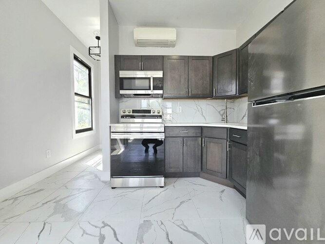 A modern kitchen with a marble floor and stainless steel appliances.