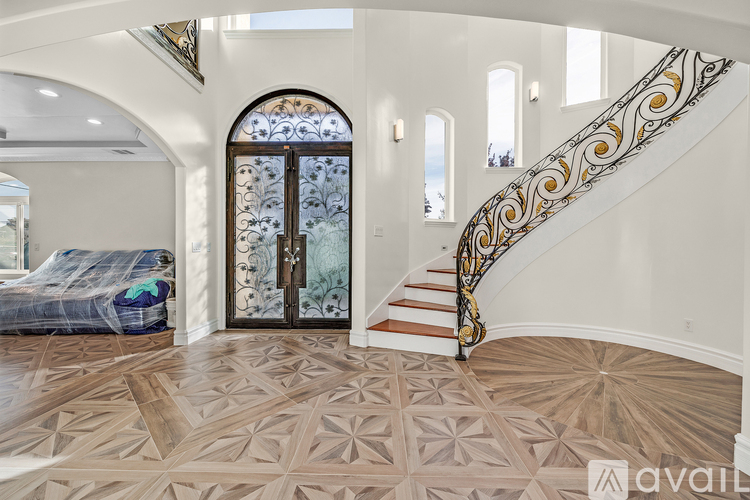 A bedroom with a large bed and a staircase with a gold railing.
