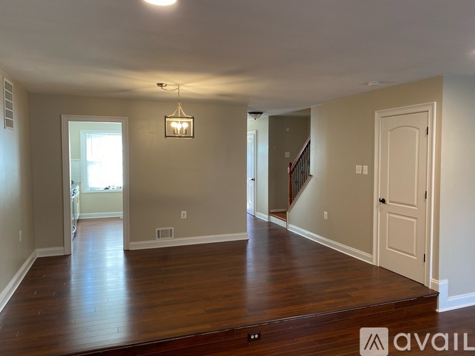 A room with wooden floors and a chandelier hanging from the ceiling.