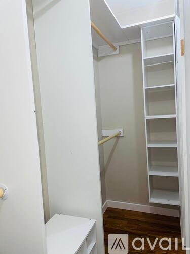 A white closet with shelves and a bench.