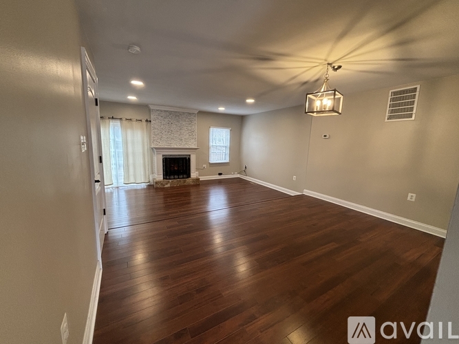 A spacious room with wood flooring and a fireplace.