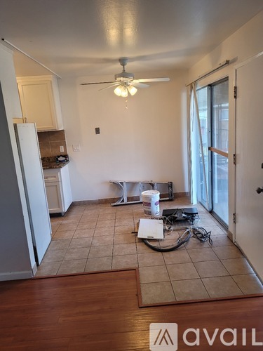 A room with a ceiling fan and a refrigerator.