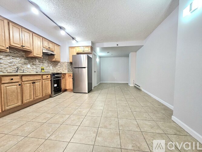A kitchen with wooden cabinets and a stone backsplash is available for rent.