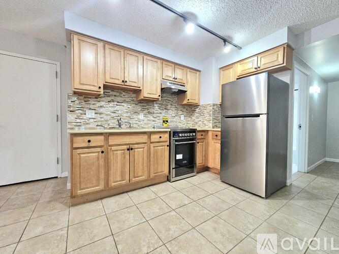 A kitchen with wooden cabinets and a stone backsplash.