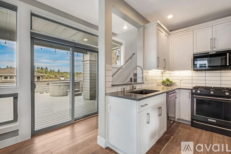 A modern kitchen with white cabinets and black appliances.