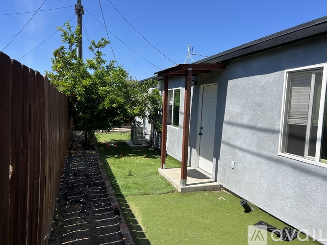 A small house with a grey exterior and a brown wooden fence.