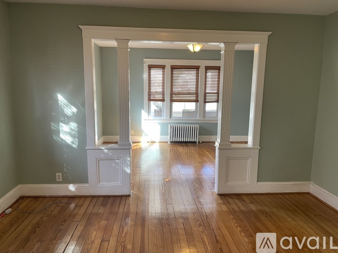 A room with wooden floors and a window with blinds.