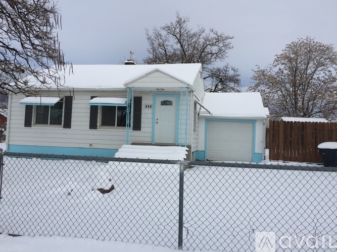 A small house with a blue door and a white fence.