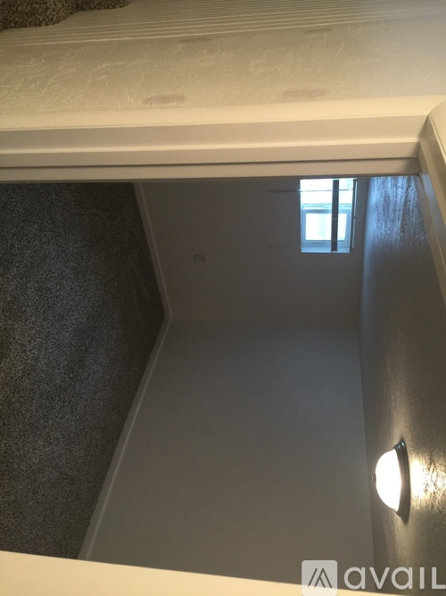 A small room with a window and a light on the wall.