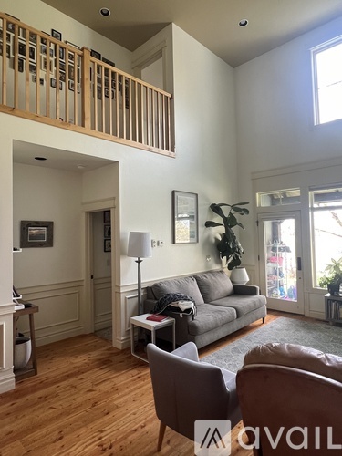 A living room with a grey couch, a brown chair, and a wooden floor.