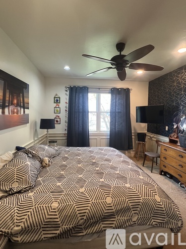 A bedroom with a patterned bedspread and a ceiling fan.