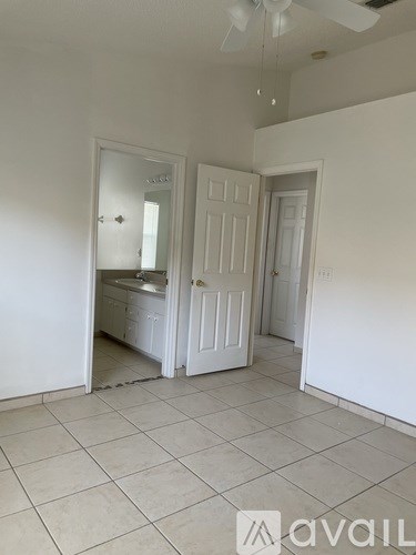 A room with a fan and a door leading to a kitchen.